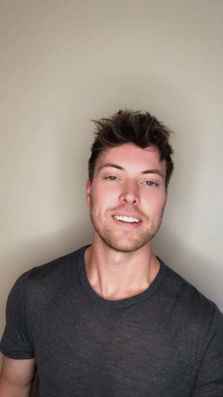 Portrait of Daniel, founder of Contract Link, smiling in a grey t-shirt against a neutral wall.