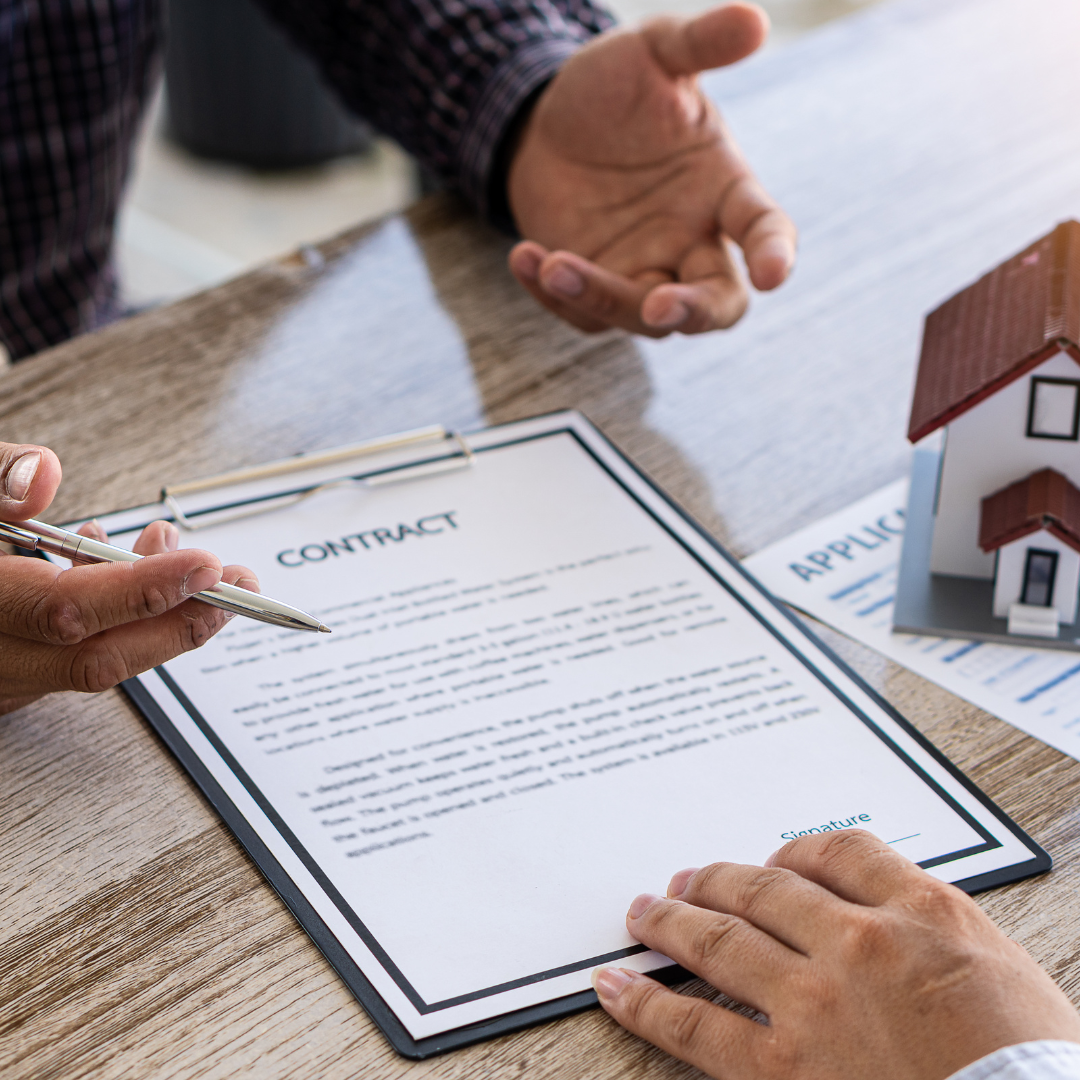 Two people reviewing a renovation contract on a clipboard at a wooden table, with a small house model in the background — the moment Contract Link is built to support.